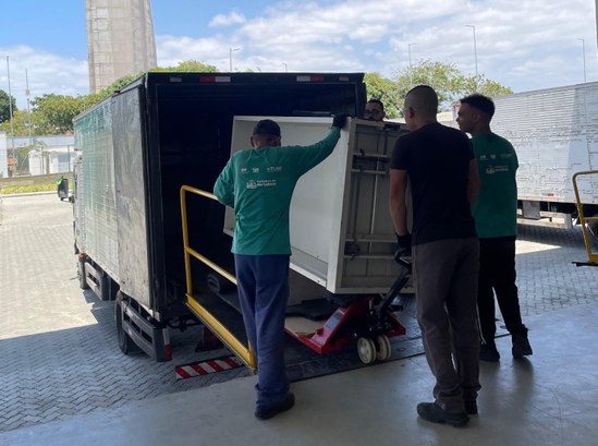 Registro fotográfico feito na sede do TRE-CE. Nele, há um grupo de quatro homens manuseando um a...